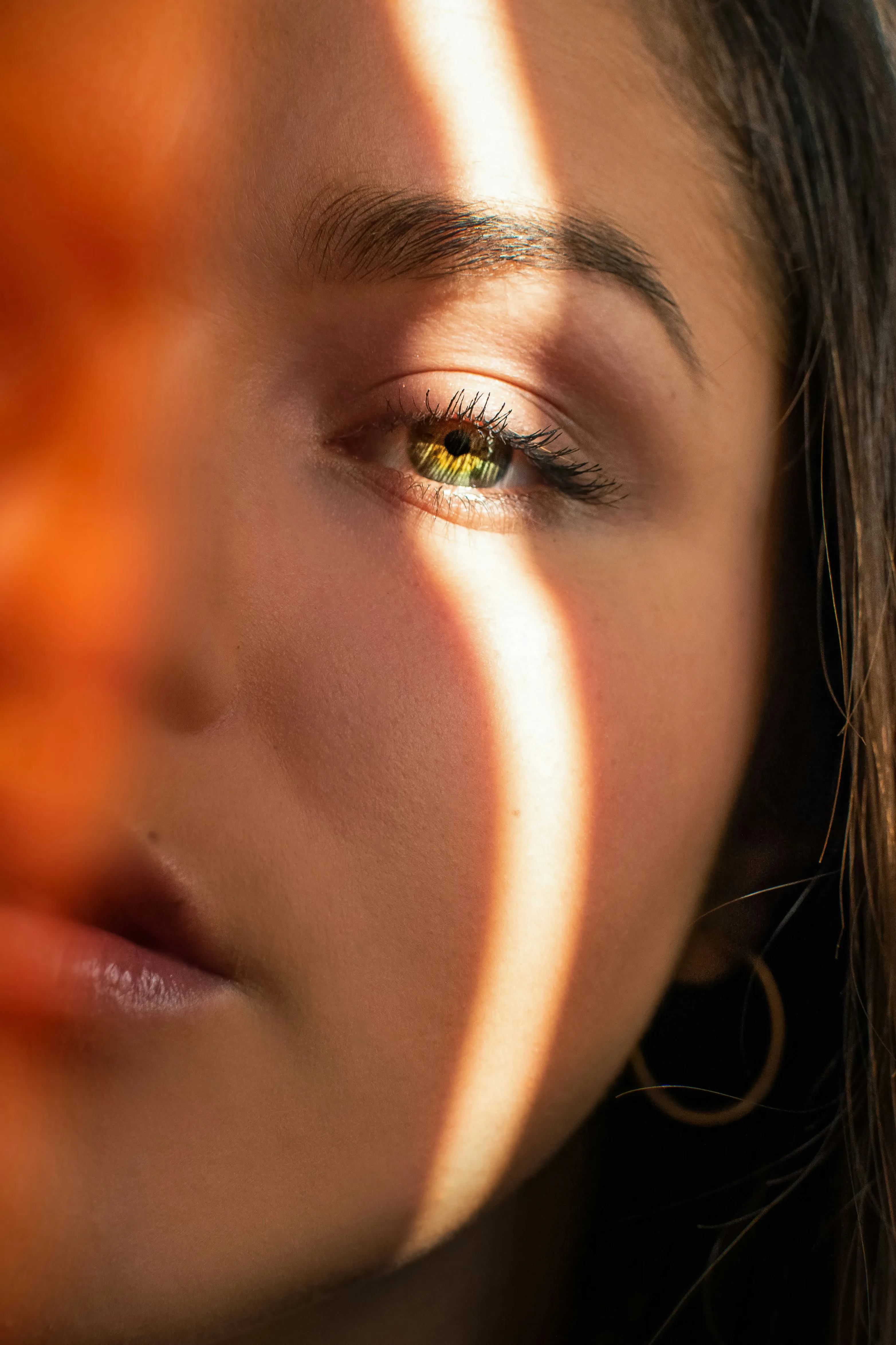 Macro detail of skin around the eye, raked by a warm band of light.
